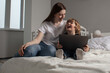 © nick_fedirko - Happy mother with her little son enjoying in online shopping or working from home. Business from distance and virtual communication.Mom and baby watch cartoons or play game on laptop on the bed.
