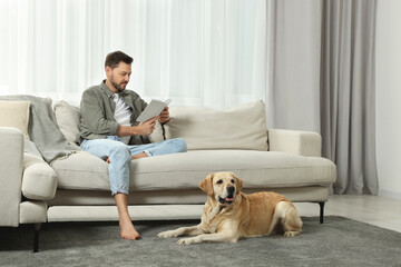 Sticker - Man reading book on sofa near his cute Labrador Retriever at home