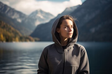 Portrait of a young woman in a hood on a background of mountains and lake