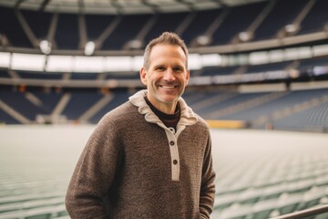 Portrait of a smiling man standing in front of an empty stadium