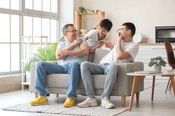 Wall Mural - Happy little boy with his dad and grandfather laughing at home