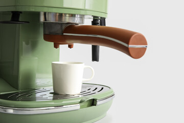 Modern coffee machine with cup on grey background, closeup