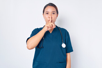 Wall Mural - Serious young Asian female nurse working wearing a blue uniform shows silence gestures isolated on white background. Healthcare medicine concept