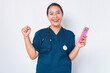 © Bangun Stock Photo - Excited young Asian woman nurse working wearing a blue uniform holding a mobile phone and celebrating success isolated on white background. Healthcare medicine concept
