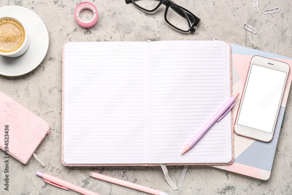 Composition with notebook, mobile phone, pens, glasses and cup of coffee on grey table