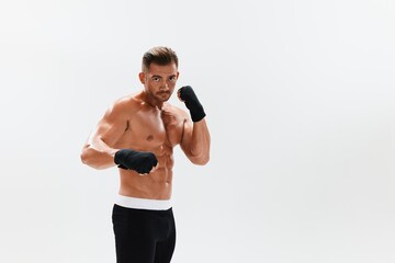 Man athletic bodybuilder poses in boxing gloves with nude torso abs in full-length background, boxing and martial arts. Advertising, sports, active lifestyle, competition, challenge concept. 