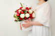 Beautiful bouquet of flowers for gift in female hands on light background