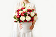 Beautiful bouquet of flowers for gift in female hands on light background