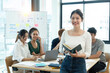 © Natee Meepian - Portrait of a happy woman standing in a corporate office during a team analysis meeting. Young businesswoman discussing and analyzing a creative project in the company conference room