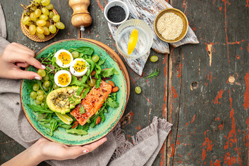 Wall Mural - keto food, salmon salad with greens, grape, eggs and avocado. Delicious breakfast or snack, Clean eating, dieting, vegan food concept. top view