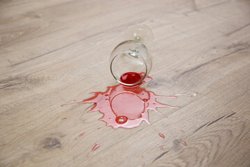 Wall Mural - Glass of red wine fell on laminate, wine spilled on floor.