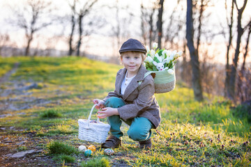 Wall Mural - Beautiful stylish toddler child, boy, playing with Easter decoration in the park, springtime