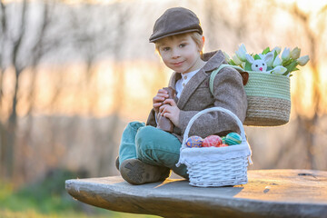 Wall Mural - Beautiful stylish toddler child, boy, playing with Easter decoration in the park, springtime