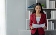 © crizzystudio - Asian businesswoman, successful entrepreneur in financial business, professional executive wearing suit holding documents View and check financial information, taxes, income within the office.