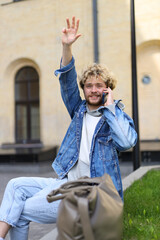 Canvas Print - The curly-haired blond raised his hand and is talking on the phone, waiting for a taxi.