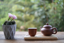 Earthenware Teapot And Tea Cup And Pink Cactus Flower On Wooden Table