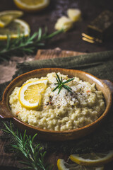 Wall Mural - Lemon rice risotto with rosemary on dark wooden background, vertical