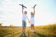 © Serhii - Running boy and girl holding two green and blue airplanes toy in the field during summer sunny day