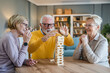 © Miljan Živković - Group of people senior man and women play leisure board game at home