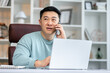 © Ivan - man talking on phone, sitting at desk with laptop, friendly manager consulting customer by phone