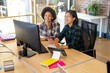 © Wavebreak Media - Two happy diverse female creatives at computer, making video call in casual office