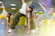 © JackF - Group of expressive teenage dancers making warming up stretching exercises for legs before dance lesson in studio