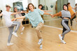© JackF - Interested modern teen boys and girls practicing dynamic boogie-woogie in pairs during group class in dance studio for youth
