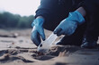 environmental pollution. Volunteer in protective gloves picks up a plastic bottle on the beach