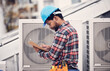 © Jordan C/peopleimages.com - Technician, checklist and air conditioning inspection on roof for safety, power and maintenance. Engineer, black man and paperwork for hvac system, ac repair or quality assurance for sustainability