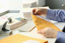 Man Holds Apaper Envelope With Business Mail At Workplace. Receiving Correspondence And Bank Notifications