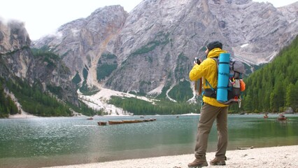 Wall Mural - young tourist hiker man taking pictures at beautiful alpine lake lago di braies ,pragser wildsee, in