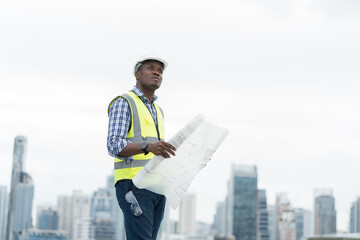 male engineer worker working, holding blueprint and inspecting structure of building at rooftop of b