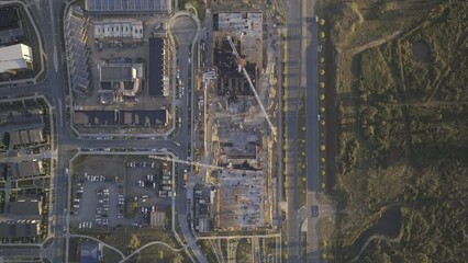 Canvas Print - Aerial footage of a construction site with tall cranes near cars driving on the roads