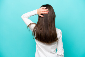 Wall Mural - Little caucasian girl isolated on blue background in back position and thinking