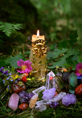 Sticker - Burning candle with sun amulet, mineral gemstones, flowers in forest, dark natural abstract background. esoteric ritual for Summer solstice, Midsummer, Litha. pagan witch tradition, wiccan practice