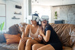 © ADDICTIVE STOCK - Excited women in VR headsets playing video game at home