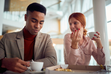 Wall Mural - A young businessman is having a friendly talk with female colleague while they enjoying coffee after a lunch in the company building together. Business, people, company