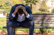 © ADDICTIVE STOCK - Black disappointed male entrepreneur sitting on bench in park