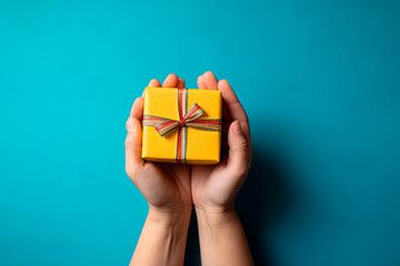 Woman hands holding gift decorated with ribbon on blue background, copy space. Flat lay, hands and present box, top view. Valentine or love, spring holidays, Christmas and birthday concept.