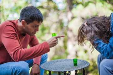 Very drunk couple, a boy and a girl, drink a strong alcoholic drink from small glasses. Bad social unhappy atmosphere