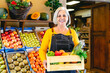 © Alessandro Biascioli - Female greengrocer working at the market holding a box containing fresh fruits and vegetables - Food retail concept