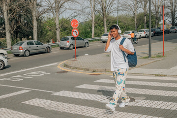 young latino male on the street walking with headphones