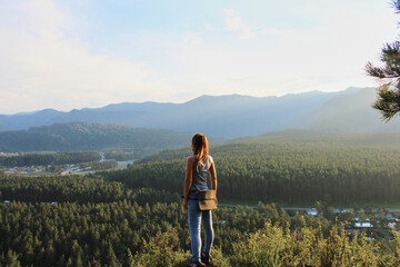 Concept woman traveler on a solo journey, standing on a hill, looking into the distance. Summer Nature landscape