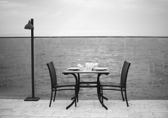 Amazing romantic dinner on the beach. Romance and love,  dinning table setup with sea view in cloudy day. Black white photo