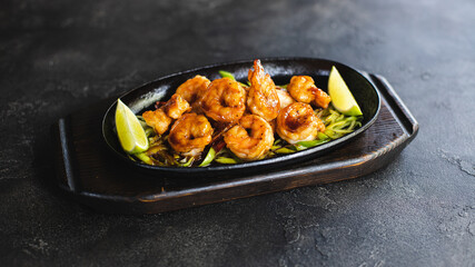 Wall Mural - Asian cuisine. Shrimps with curry noodles. Appetizing dish on a dark background