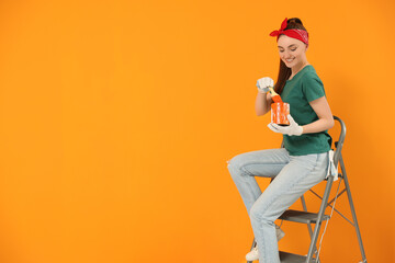 Wall Mural - Happy designer with brush taking paint from can near orange wall, space for text