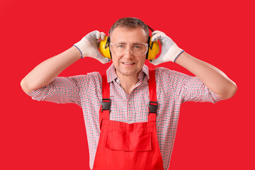 Canvas Print - Mature carpenter in hearing protectors on red background