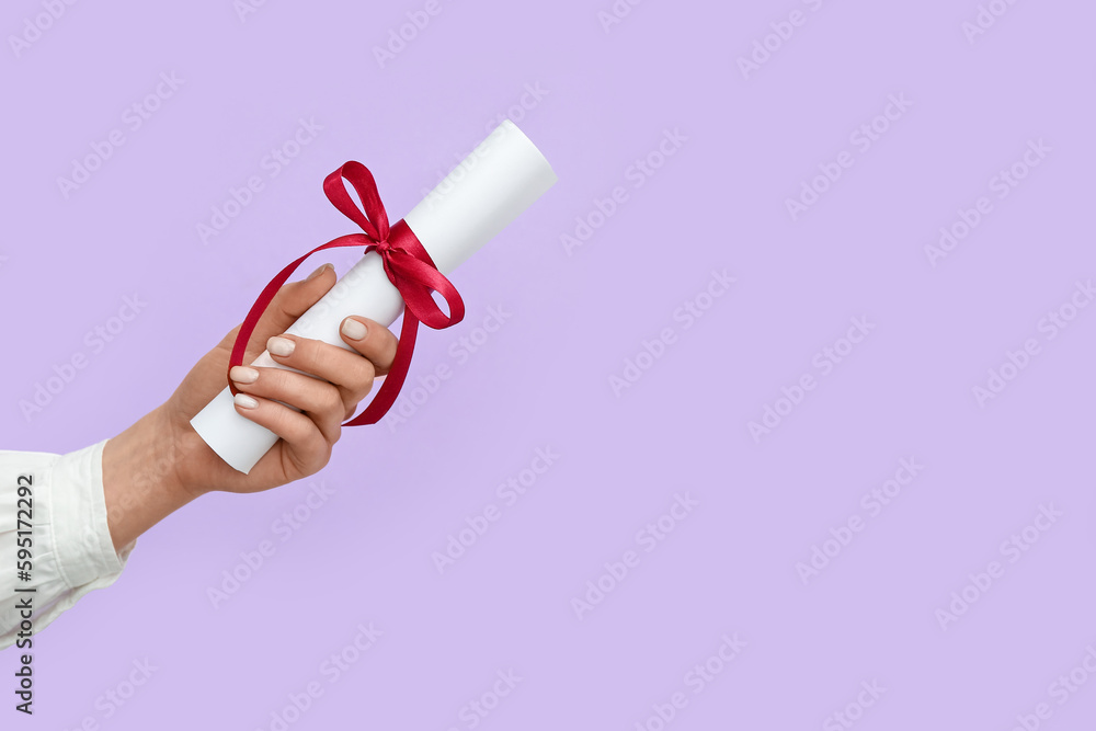Woman holding diploma with ribbon on lilac background