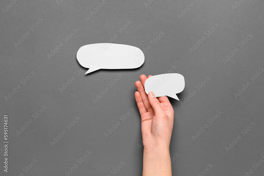 Woman holding blank speech bubble on dark background