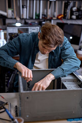 Wall Mural - young professional repairman unscrewing screws from computer case with screwdriver for repair and maintenance. repair and maintenance of computers, pc. concentrated caucasian guy at workshop